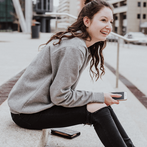 College student sits outside with phone