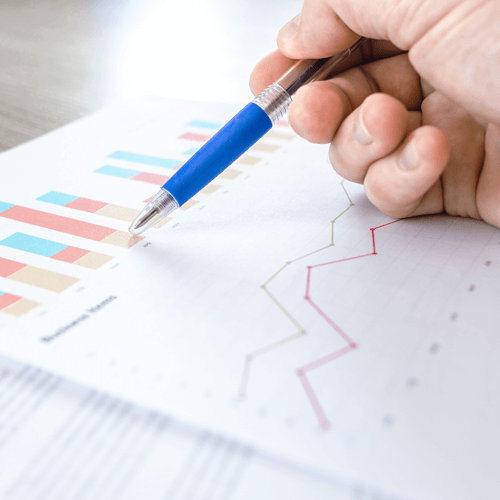 Hand using a pen to point at a bar graph printed on paper