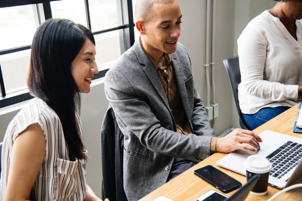 Young man and woman smiling at a computer in an office