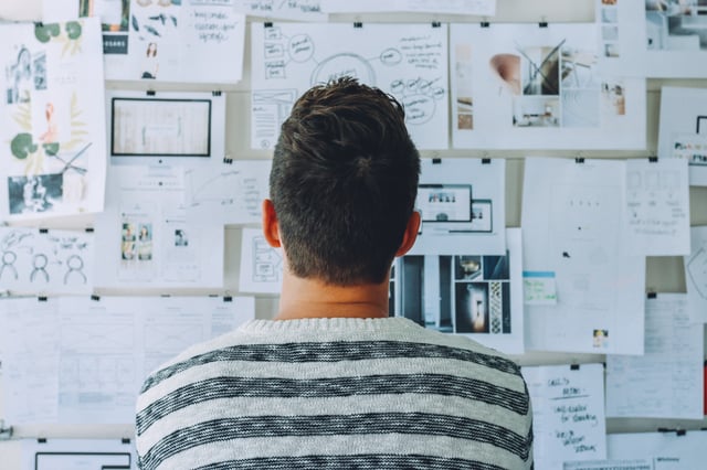 Man looking at a whiteboard filled with papers depicting a content strategy session
