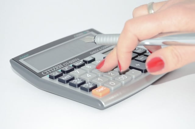 Woman’s hand using a calculator to figure out the cost of hiring employees