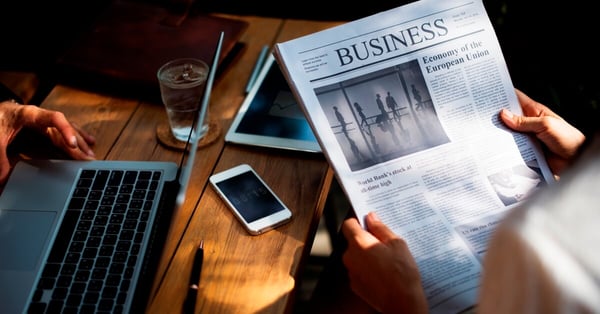Image of person reading the business section of a newspaper, representing how whitespace and visual structure can make reading important text more appealing.