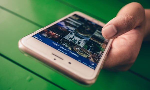 Image of a hand holding a smartphone with a photo gallery to represent using visuals in your blog posts.