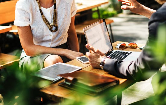 Business man and woman talking over a laptop computer portraying a business relationship